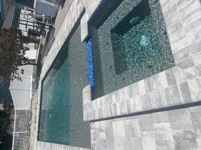 Rectangular pool and integrated square spa with blue mosaic glass tiles
