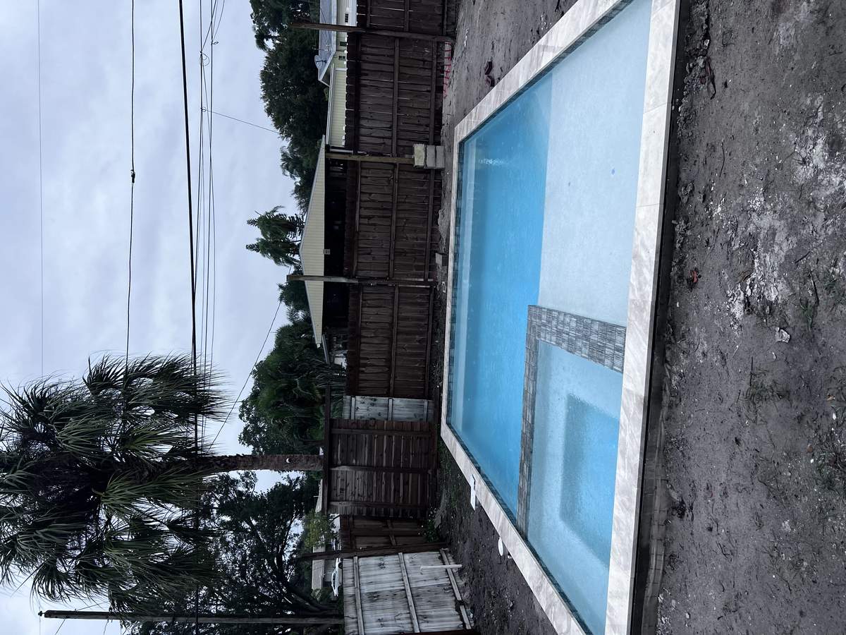 Close-up of water-filled custom pool shell and stone coping during active build