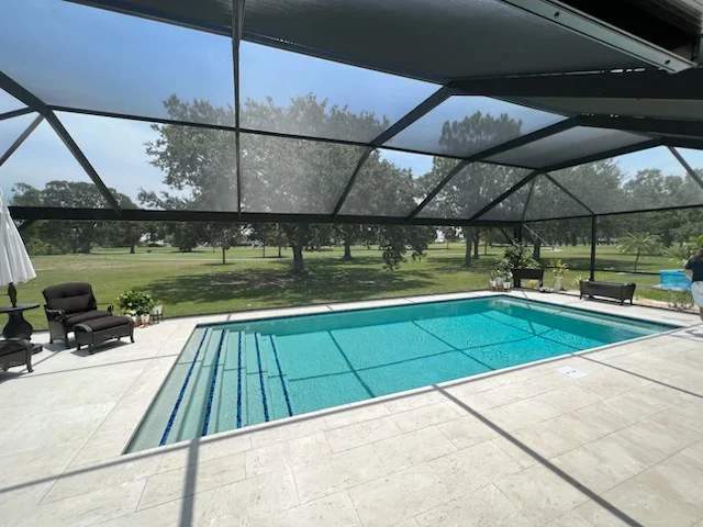 Rectangular pool with wide concrete steps entry under a black screen enclosure