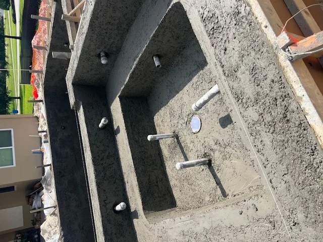 Active construction view showing a freshly shot concrete spa shell and pipes