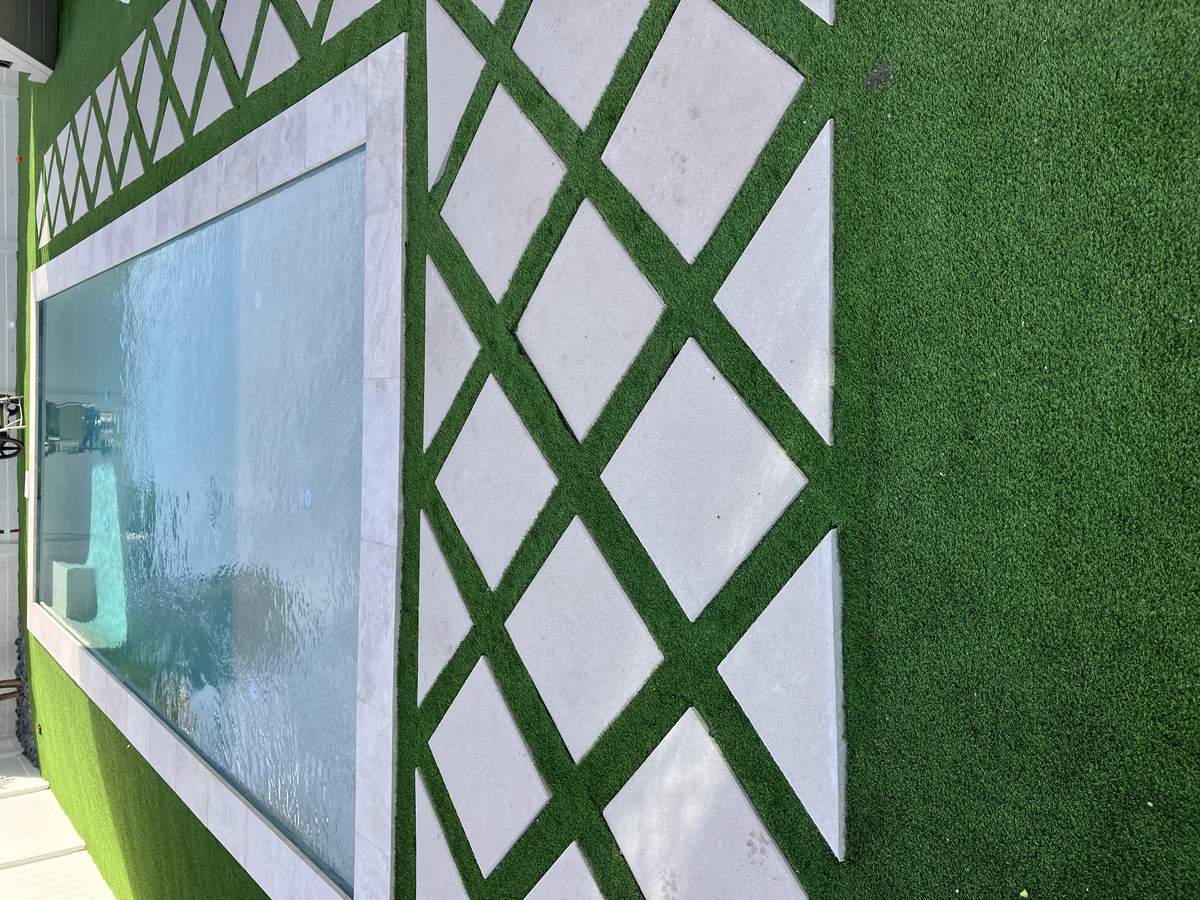 Custom pool deck renovation featuring diamond pavers bordered by artificial turf