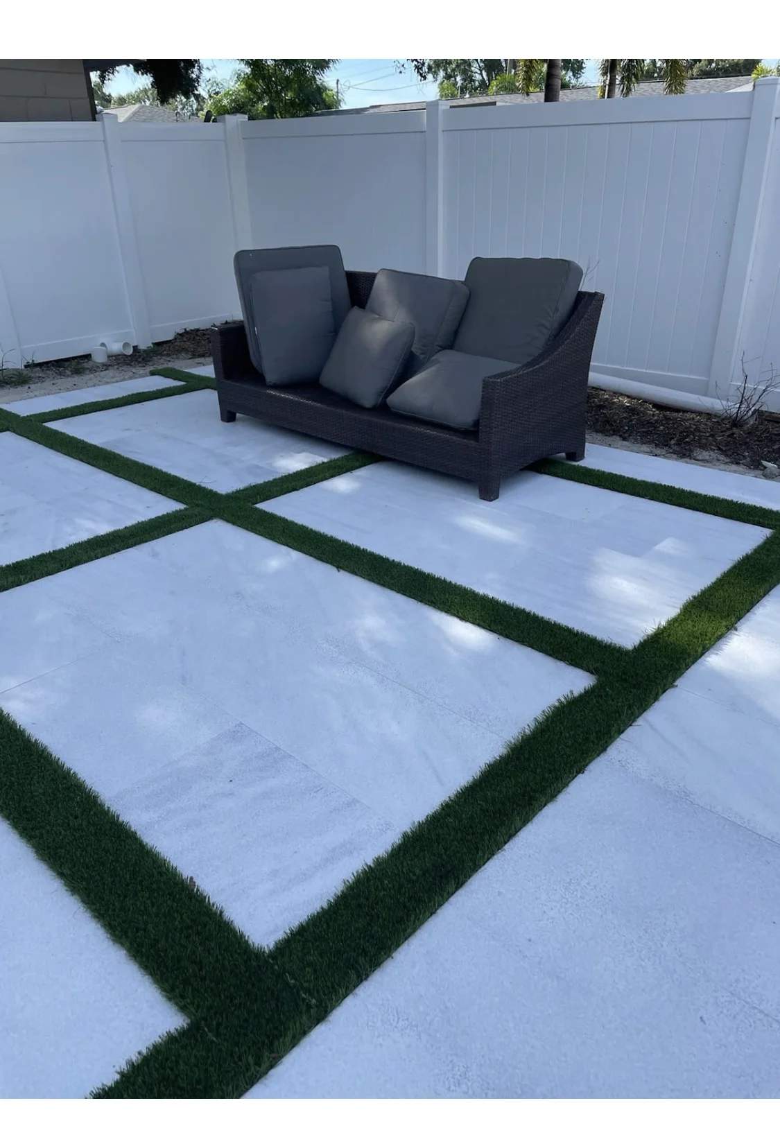 Close-up details of large white square concrete pavers bordered by green turf grids