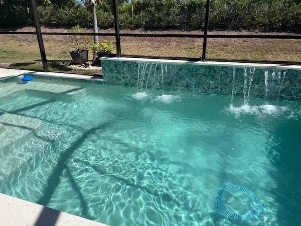Completed pool renovation featuring three sheet waterfalls and turquoise mosaic wall