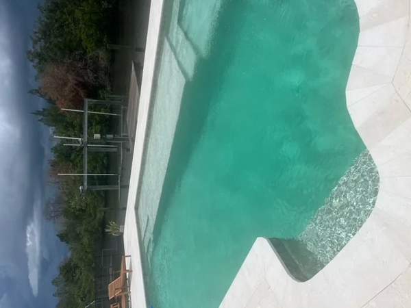 Shimmering turquoise pool with sun shelf overlooking a coastal waterway canal