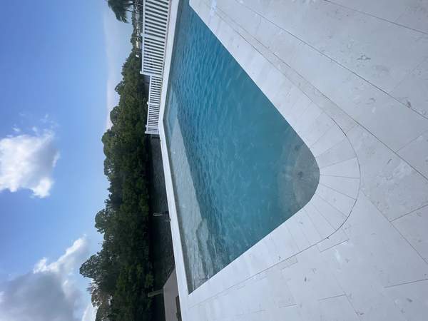 Finished rectangular concrete pool next to a waterway canal with travertine decking