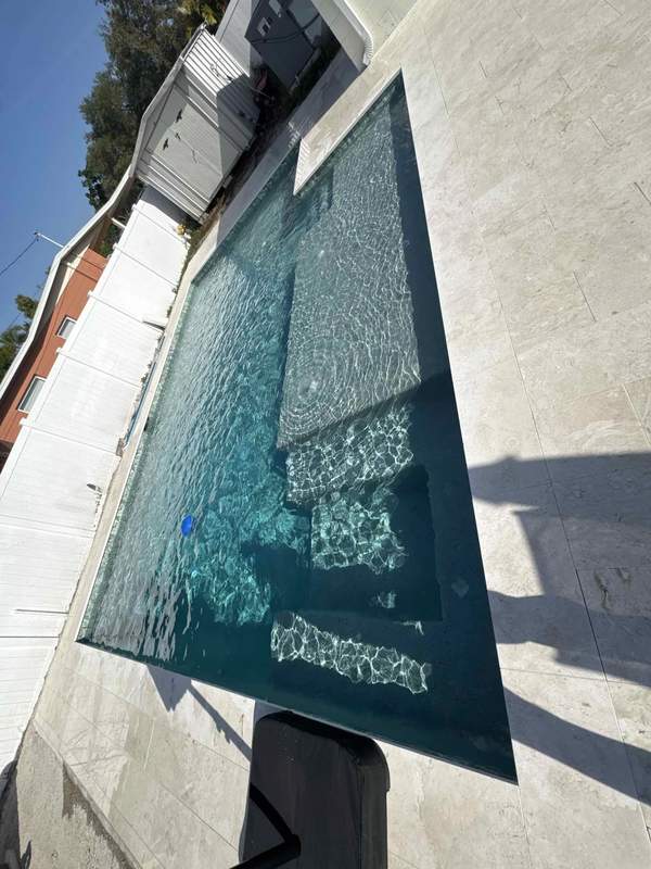 Custom pool with dark pebble finish, long sun shelf, and active water bubbler jets