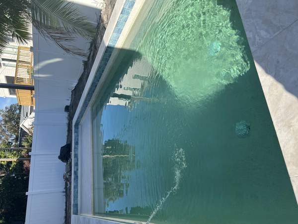 Rectangular pool shell under construction next to a white boundary fence