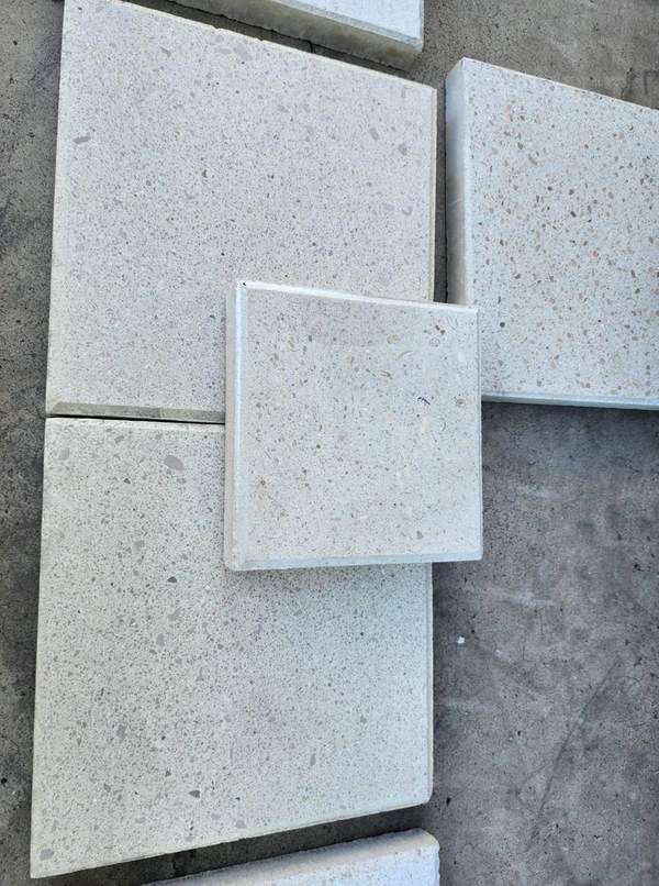 Samples of textured square limerock concrete pavers displayed on concrete