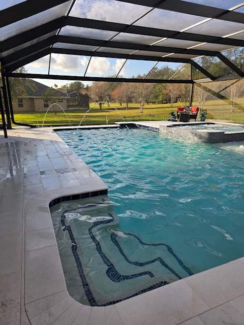 Rectangular pool under screen enclosure with three fountains, travertine, and spa