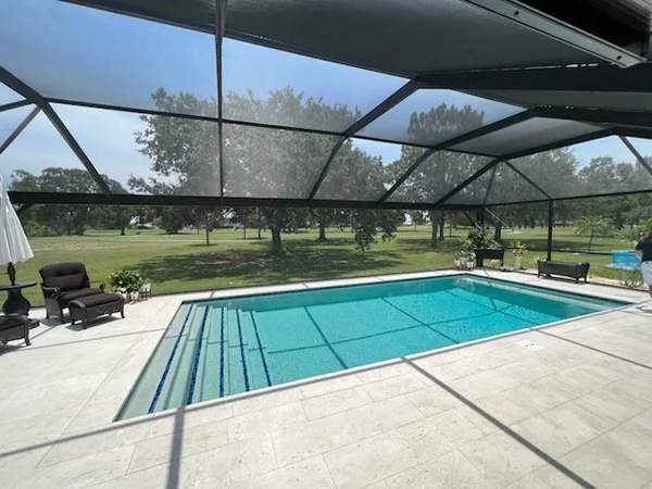 Rectangular pool under screen enclosure with wide steps spanning the near end