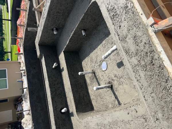 Active construction view showing a freshly shot concrete spa shell and pipes