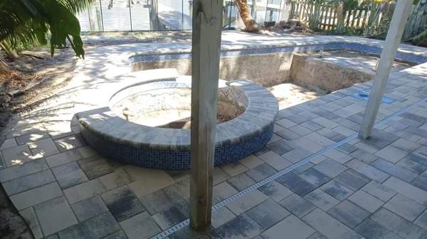 Under-construction custom pool showing grey stone pavers deck and circular spa shell