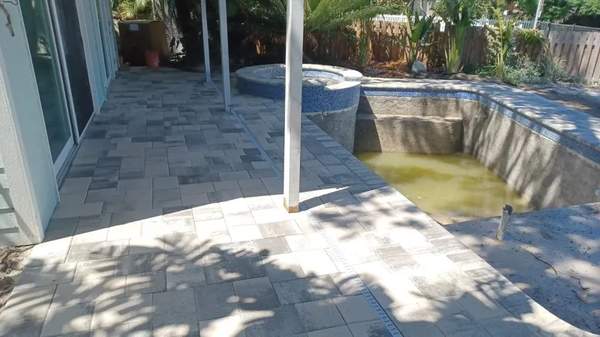 Side angle of concrete pool shell and raised spa under construction next to a canal