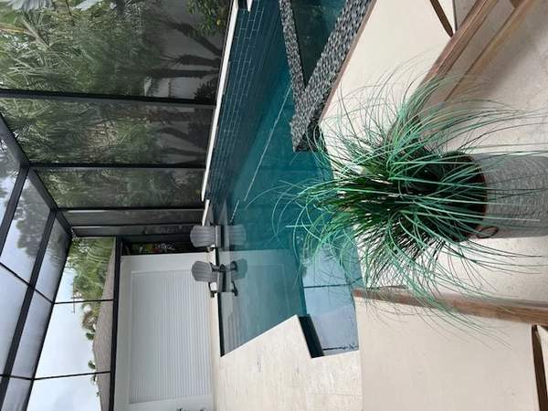Contemporary rectangular pool with dark blue glass tile wall and built-in spa