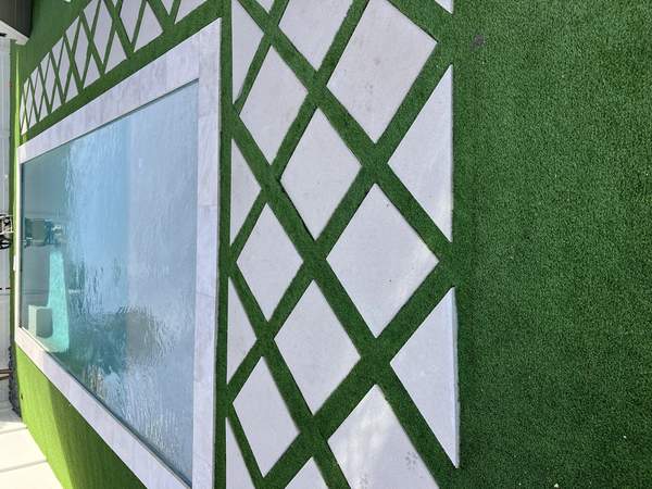 Custom pool deck renovation featuring diamond pavers bordered by artificial turf