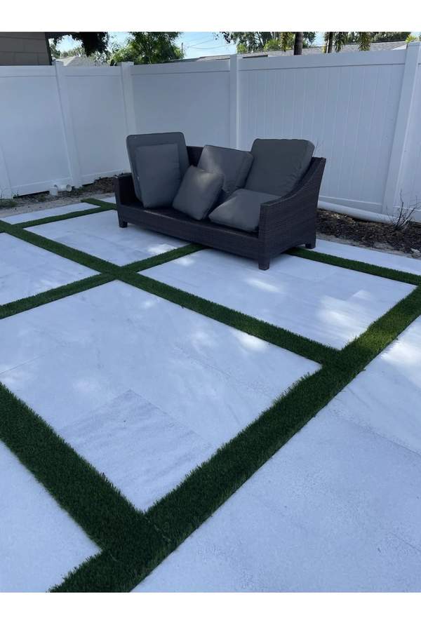 Close-up details of large white square concrete pavers bordered by green turf grids