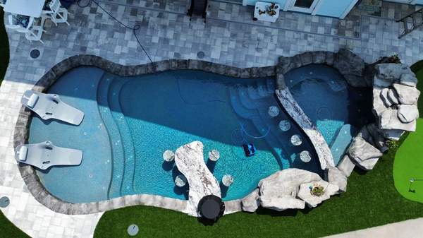 Top-down drone view capturing the entire pool shell, swim-up table, and spa