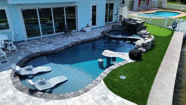 High-angle shot highlighting in-pool lounge chairs, swim-up bar, and sea wall